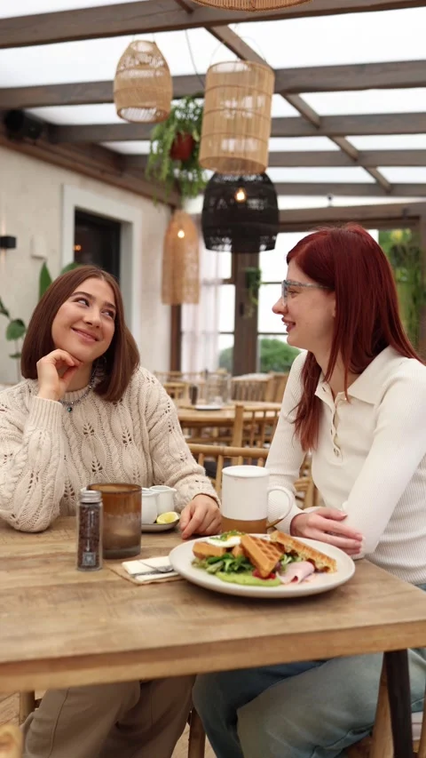 Vertical screen two women sit together in a cozy cafe  Stock Footage 320827134