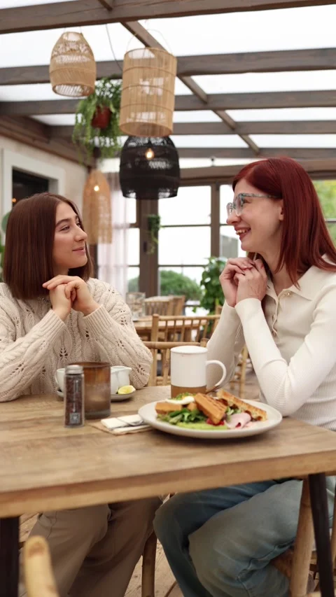 Vertical screen two women sit in a cozy cafe smiling warmly  Stock Footage 320827139