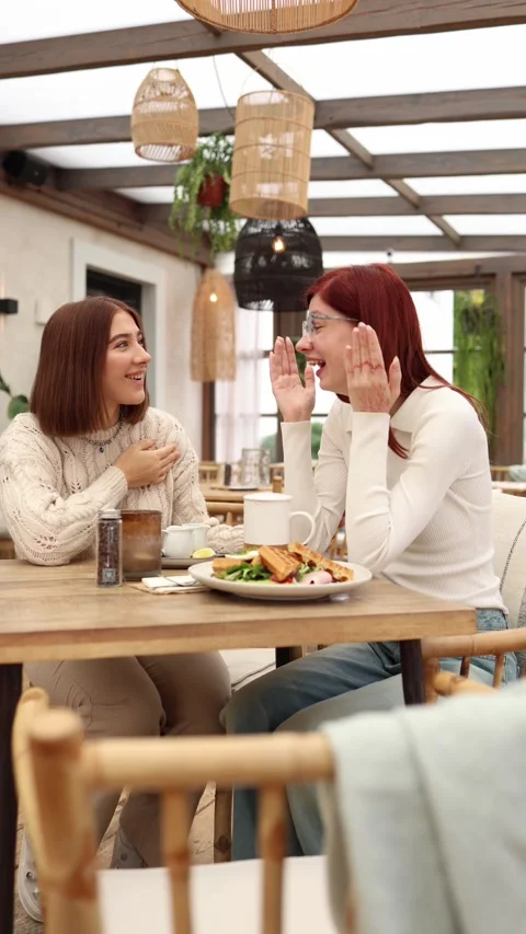 Vertical screen two young women sit in a cafe laughing  Stock Footage 320827149