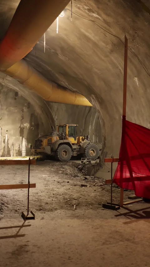 Vertical screen underground tunnel scene with yellow loader parked on rough dirt Stock Footage 309653384