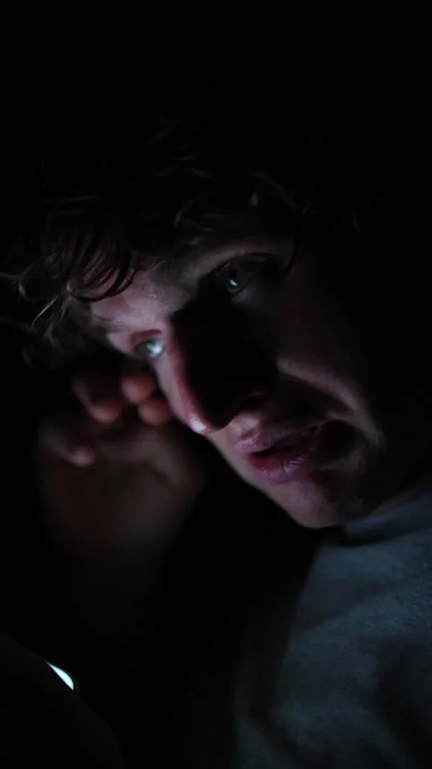 Vertical screen Upset man reacts to something on his phone in the dark holding h Stock Footage 313842829