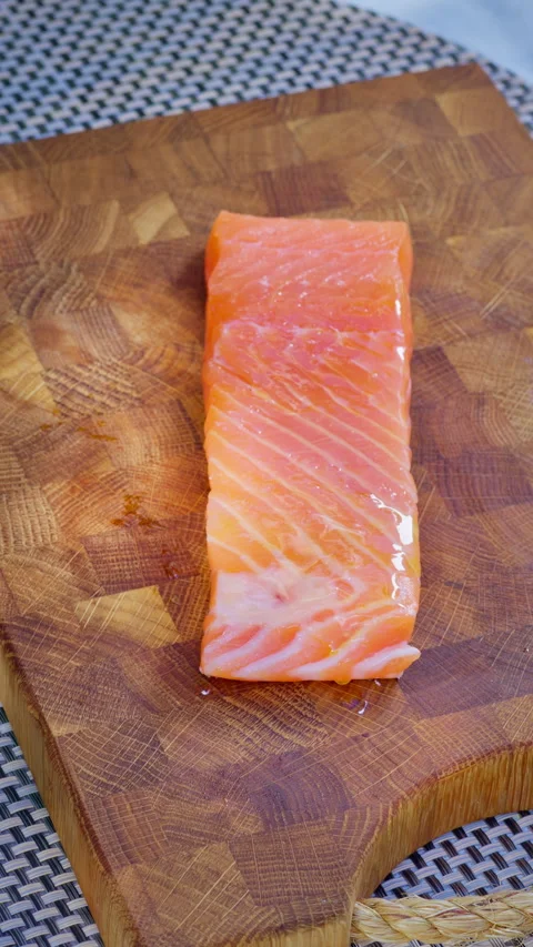 Vertical screen video. Close-up of a chef brushing a salmon steak with olive oil Stock Footage 315268721