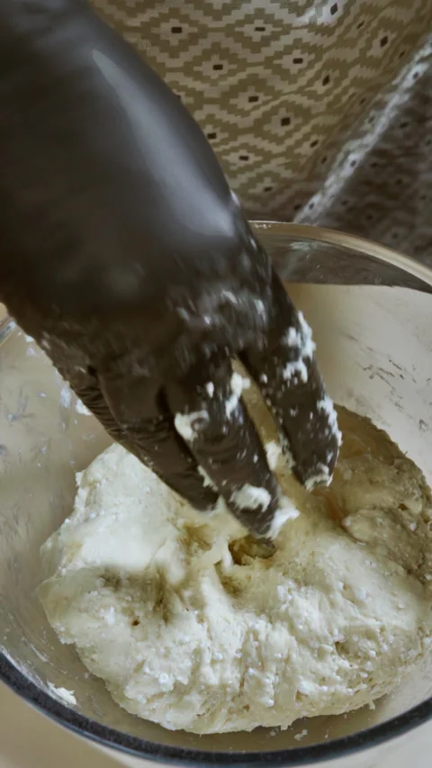 Vertical screen video. A woman's hand kneads cookie dough in a large glass bowl. Stock Footage 299633848