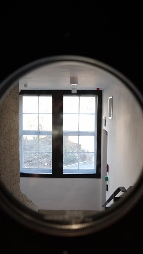 Vertical screen: A view through a circular frame reveals a bright stairwell with Stock Footage 304459358