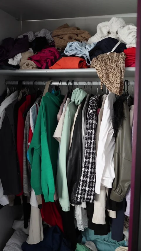 Vertical screen: A wardrobe packed with clothes—folded, hanging, and some spilli Stock Footage 300021592
