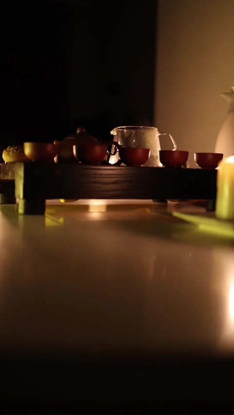 Vertical screen: A warm tea ceremony setup with a clay teapot, small cups, and a Stock Footage 299380683