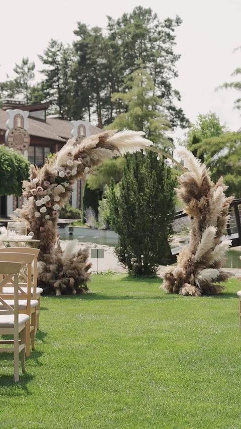 Vertical screen: Wedding arch setup with wooden chairs on a lawn. Wedding decor Stock-Footage 308396135