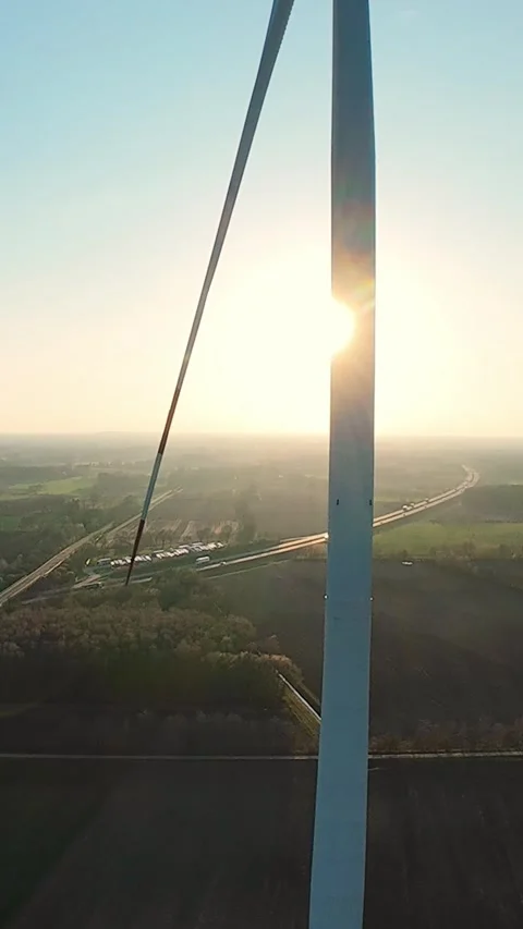 Vertical screen. Wind turbine with sun flare shining through rotating blades Stock Footage 325059600