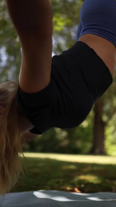 Vertical screen Woman hangs upside down in aerial yoga pose with focused express Stock Footage 313378799