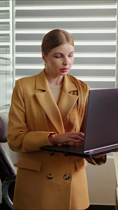 Vertical Screen Woman looking at laptop screen then smiling on camera in office Video stock 299983405