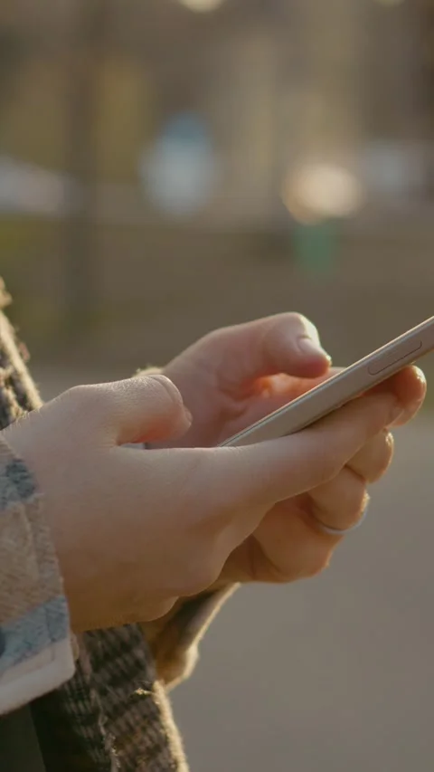 Vertical Screen Woman using smartphone in park at sunset Stock Footage 303564272