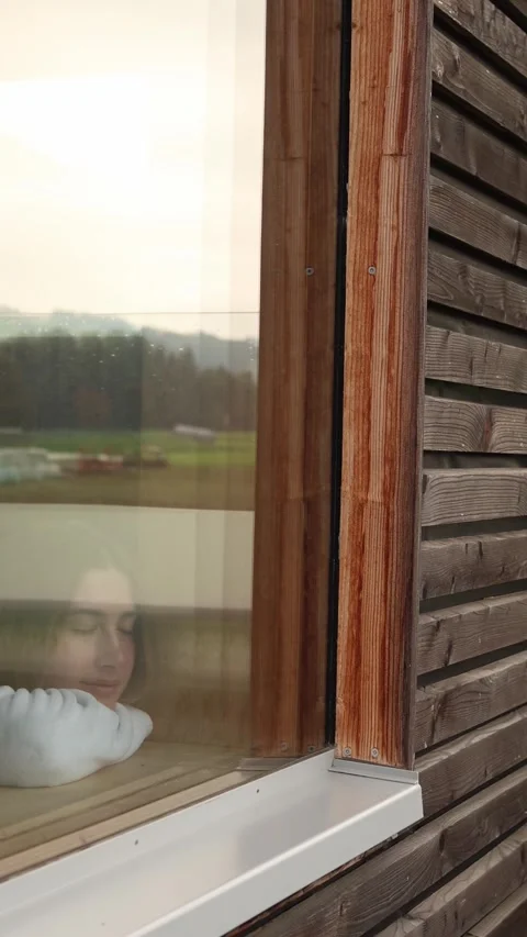 Vertical screen woman in white bathrobe leans by wooden spa window with eyes clo Stock Footage 318219581
