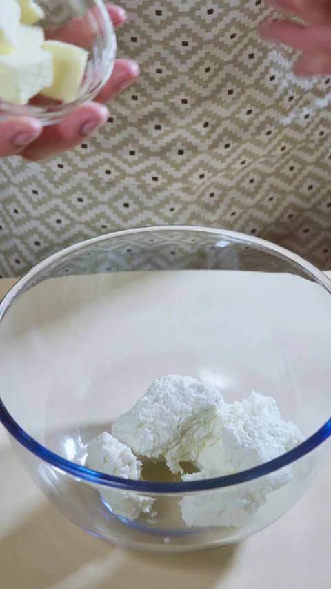 Vertical screen. A woman's hand pours butter cut into pieces into a glass bowl. Stock-Footage 299634651