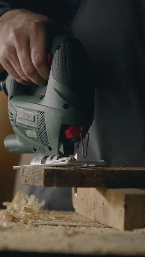 Vertical screen. Wood sawdust, Workshop employee cuts hole with electric jig Stock Footage 331737926