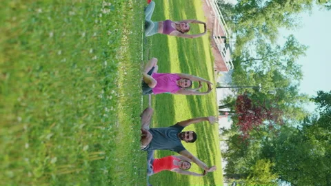 Vertical Screen: Yoga trainer with students practicing twist poses Stock Footage 248758532