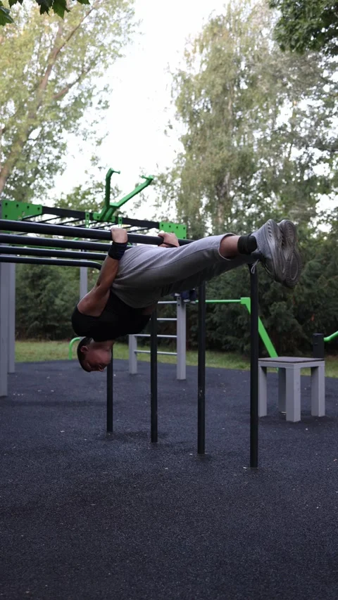 Vertical screen young athlete performs front lever on parallel bars in outdoor p Stock-Footage 316700730