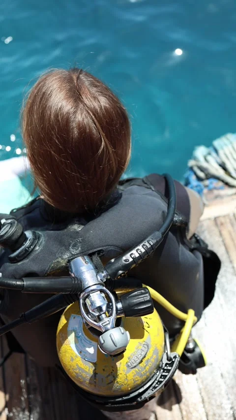 Vertical screen young diver sits on boat edge in full scuba gear with sunlit oxy Stock Footage 310485512