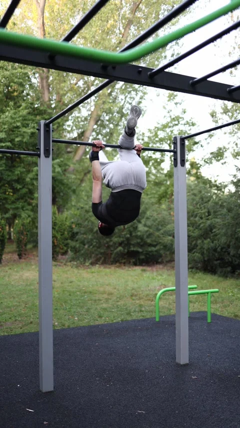 Vertical screen young guy performs explosive muscle up on outdoor bar in park wo Stock Footage 316700885