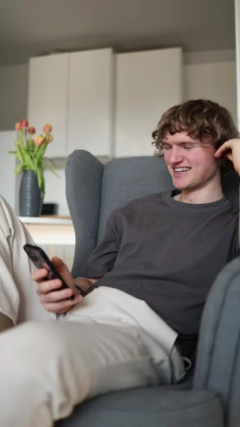 Vertical screen: Young man enjoying good times alone, smiling cheerfully at his  Stock Footage 302632269