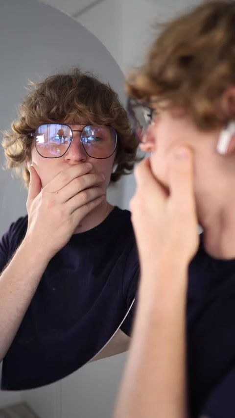 Vertical screen young man examines his reflection with a serious expression anal Stock Footage 313268914