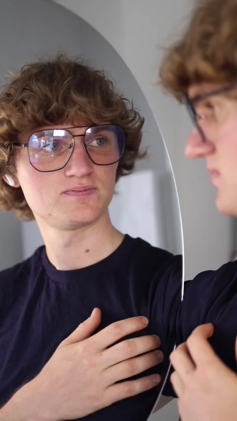 Vertical screen young man gently places his hands on his chest looking down with Stock Footage 313268904