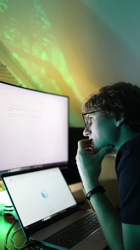 Vertical screen young man in glasses leans on his hand while focusing on compute Stock Footage 316878121