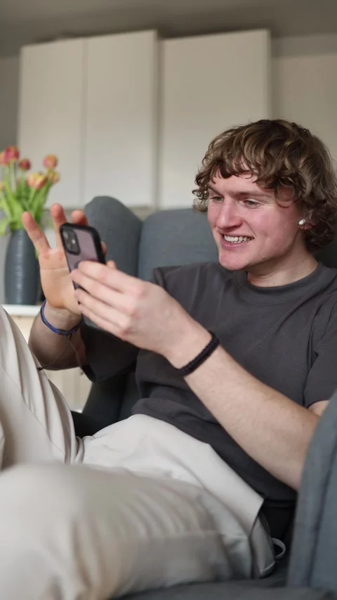 Vertical screen: Young man laughing hard at a funny social media video on his sm Stock Footage 302632300