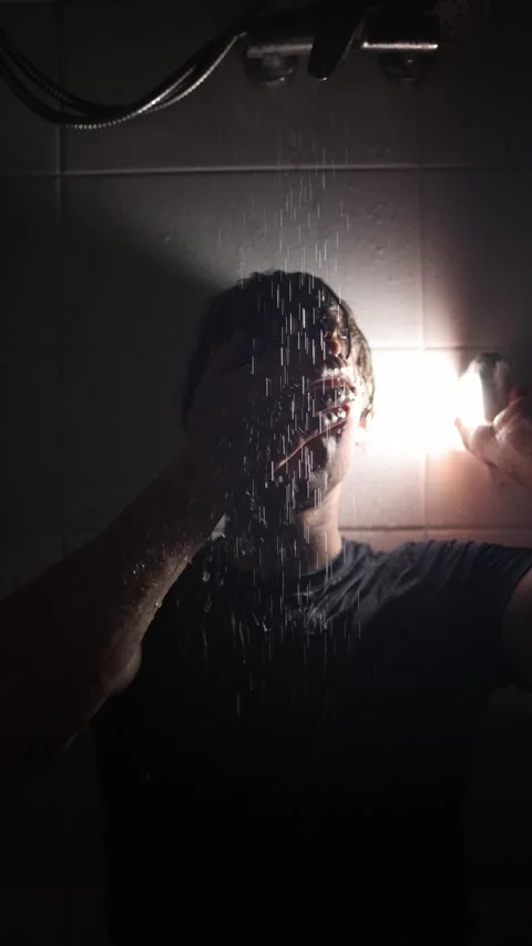 Vertical screen young man stands under shower streams hand covering mouth water  Video stock 316066377