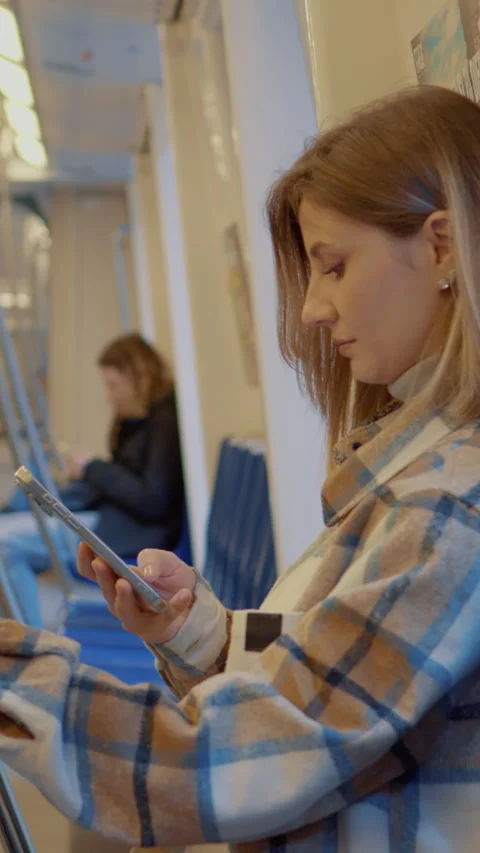 Vertical Screen Young mother using smartphone while traveling on subway with Stock Footage 303566069