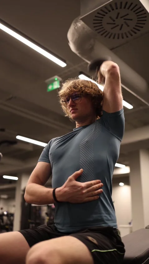 Vertical screen: A young student is performing a tricep extension exercise in th Stock Footage 301676919