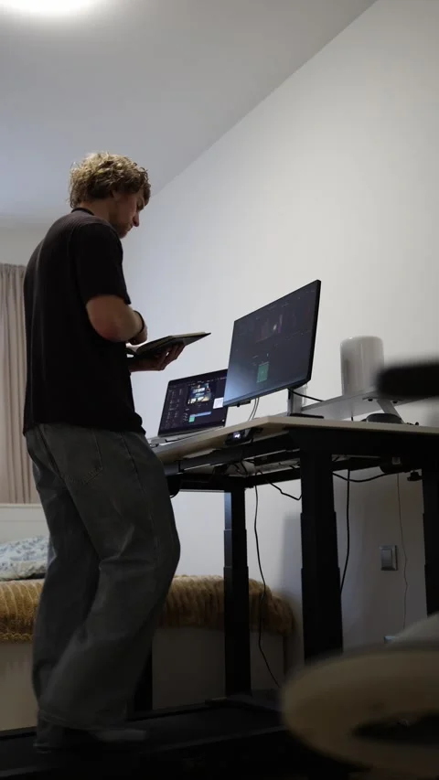 Vertical screen young video editor raises his standing desk while walking on a t Stock Footage 346880736