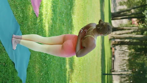 Vertical Screen: Young woman practicing stretching exercises in sunny city park Stock Footage 248991767