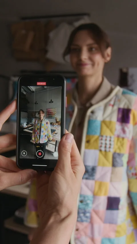 Vertical of Seamstress Filming Apprentice Trying on Patchwork Jacket Stock Footage 315770296