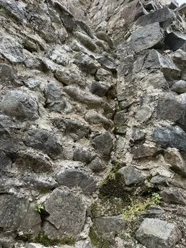 Vertical section of an old stone wall with visible mortar, erosion, moss Stock Photos