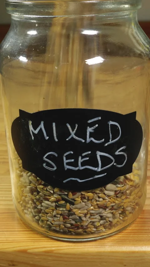 Vertical – A seed mix being poured into a glass storage jar with named label. Stock Footage 283465633