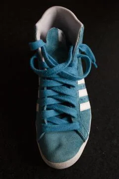 A vertical selective closeup shot of a blue and white sports sneakers on a bl Stock Photos