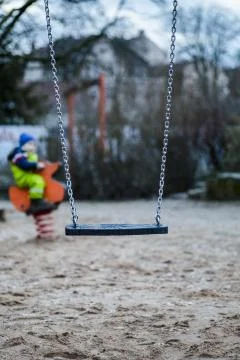 Vertical selective focus shot of a swing in a park with a blurry background Foto stock