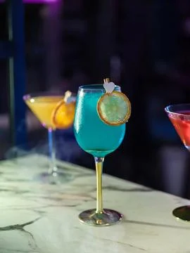 Vertical selective focus of a vibrant blue cocktail on a marble bar Stock Photos