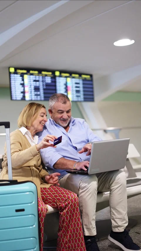 Vertical Senior Couple Using Credit Card and Laptop at Airport Stock Footage 300858980