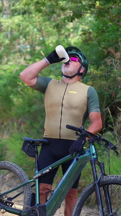 Vertical Senior cyclist drinking water from bottle on his e-bike Stock Footage 312067621