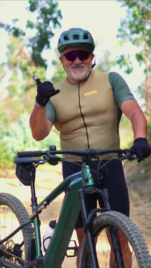 Vertical Senior cyclist making the shaka sign on his e-bike Stock Footage 312067616