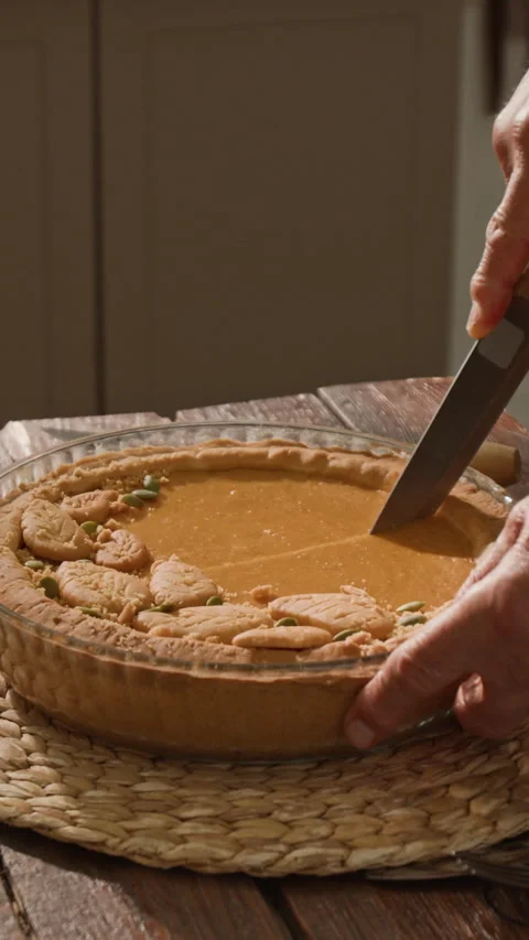 Vertical of Senior Man Cutting Homemade Pumpkin Pie for Thanksgiving Dinner Stock Footage 341392161