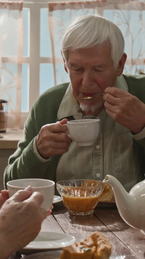 Vertical of Senior Man Eating Jam and Drinking Tea with Wife at Breakfast Stock Footage 341394708