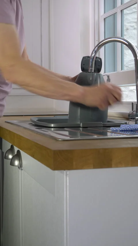Vertical - A senior man’s hand adding water to a kettle from a kitchen sink tap. Stock-Footage 288337091