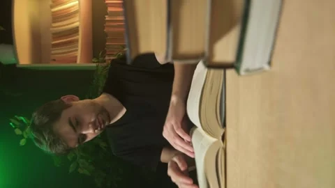 Vertical shooting, a guy is reading a book in the library Stock Footage 264882547