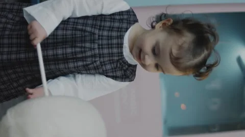 Vertical shooting of a smiling happy little girl holding the cotton candy in her Stock Footage 252224943