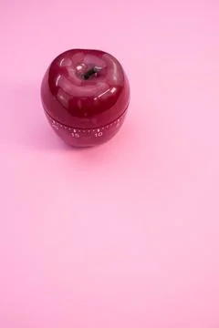 Vertical shot of an apple-shaped kitchen timer isolated on pink background Stock Photos