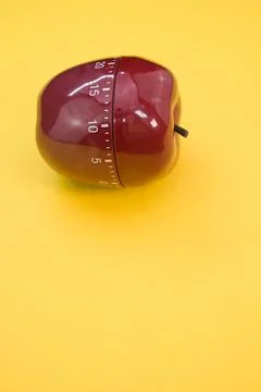 Vertical shot of an apple-shaped kitchen timer isolated on yellow background 스톡 사진