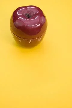 Vertical shot of an apple-shaped kitchen timer isolated on yellow background Stock Photos