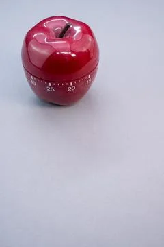 Vertical shot of apple-shaped kitchen timer isolated on light blue background Stock Photos